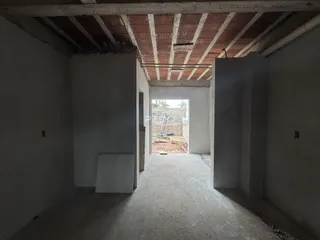 Vista interna de um corredor com teto de madeira aparente em uma propriedade.