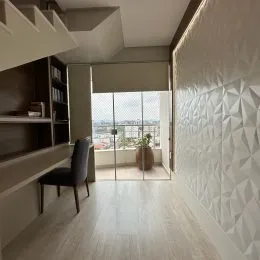 Foto de um corredor interno com piso de madeira clara e escadaria.