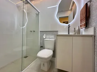 Banheiro moderno com box de vidro e vaso sanitário branco.