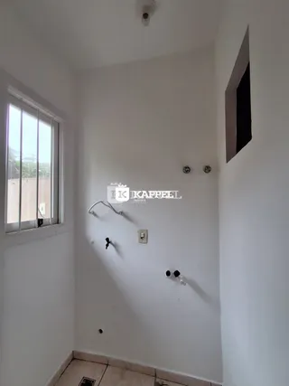 Foto de um corredor interno com janela e paredes brancas.