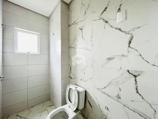 Foto de um banheiro com revestimento de azulejos brancos e detalhes em mármore.