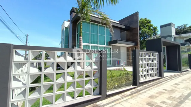 Fachada moderna de uma residência com cerca de ferro e vidro em Lajeado.