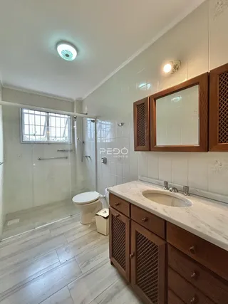 Foto de um banheiro com revestimento cerâmico e box de vidro.