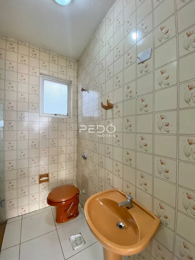 Um banheiro com revestimento de azulejos brancos e piso claro.