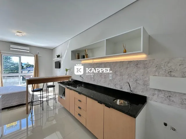 Vista de uma cozinha moderna com bancada escura e armários de madeira clara.
