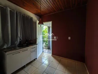 Vista interna de uma cozinha com armários brancos e piso de cerâmica.