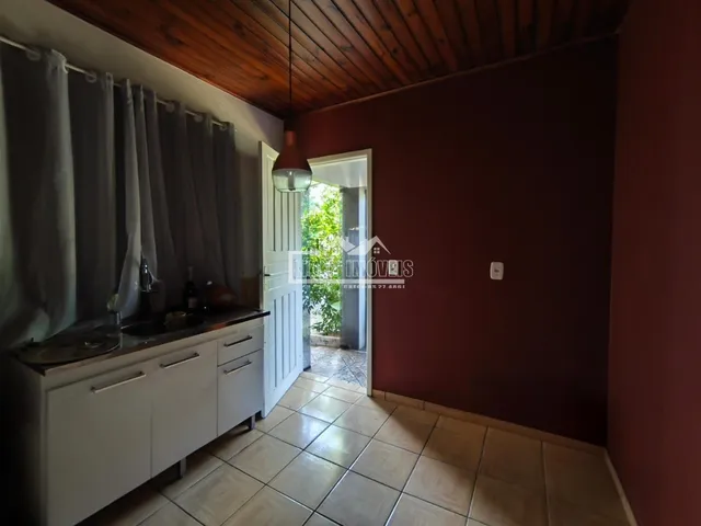 Vista interna de uma cozinha com armários brancos e piso de cerâmica.