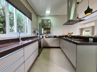 Vista interna de uma cozinha com armários e bancadas em um imóvel.