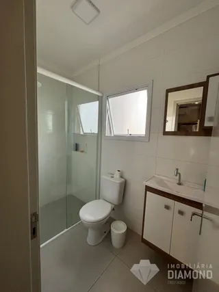 Foto de um banheiro interno com box de vidro e vaso sanitário.