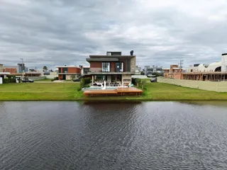 Vista da fachada de uma casa moderna em Lajeado, Brasil, com área gramada e água em primeiro plano.