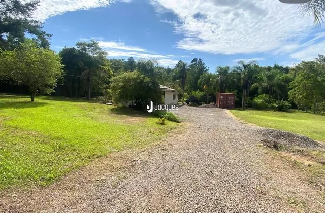 Vista externa da propriedade com gramado e acesso de cascalho.