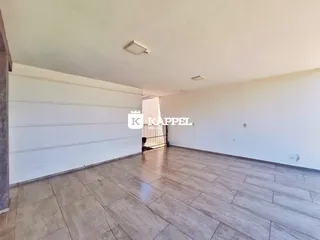 Foto de um cômodo amplo com paredes brancas e piso de porcelanato claro.