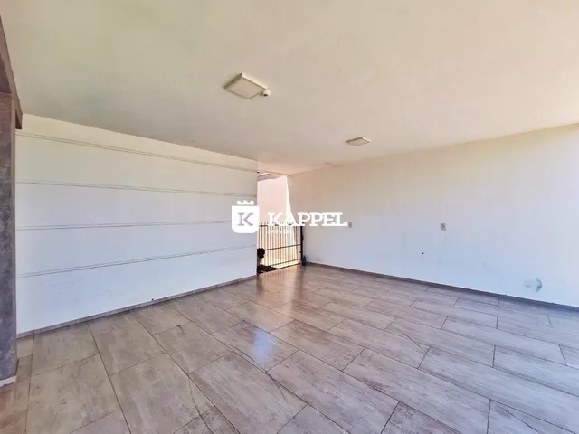 Foto de um cômodo amplo com paredes brancas e piso de porcelanato claro.