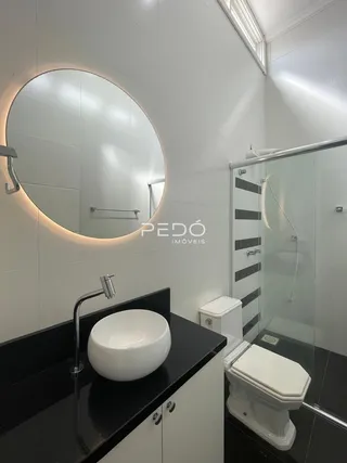 Banheiro moderno com bancada preta e box de vidro transparente.