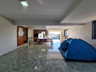 Sala ampla com piso de porcelanato e estrutura de madeira no interior da residência.