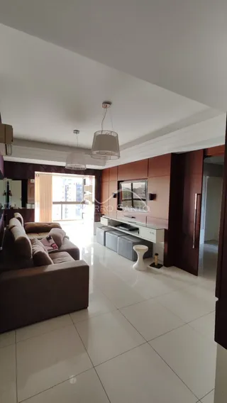 Sala de estar com sofá e piso claro em um apartamento em Lajeado.