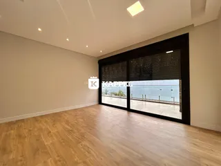 Sala de estar com piso de madeira e porta de vidro que oferece vista para o exterior.