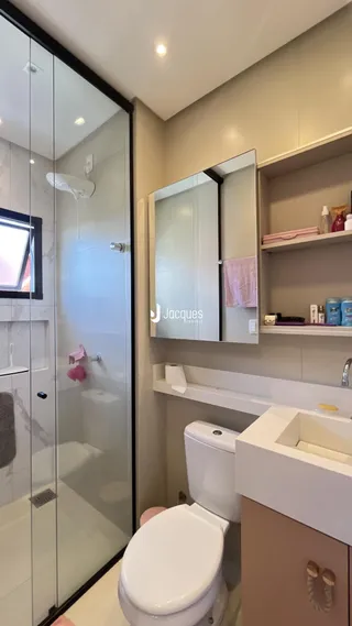 Foto de um banheiro com box de vidro e vaso sanitário em uma residência.