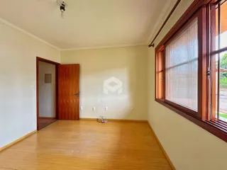Uma sala de estar com piso de madeira clara e grandes janelas.