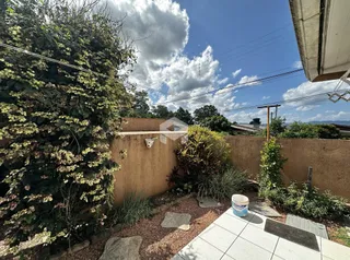 Vista externa de um jardim com muro e vegetação.