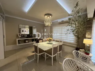 Ambiente interno de uma sala de jantar com mesa e cadeiras.