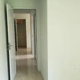 Corredor interno com paredes claras e porta visível.