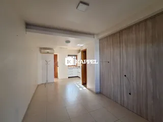 Hall de entrada com piso claro e armários de madeira.