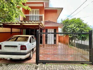 Fachada de uma casa em Lajeado, Brasil, com portão de ferro e carro estacionado na frente.