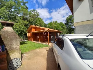 Vista externa de uma propriedade com um jardim gramado e uma estrutura de madeira.