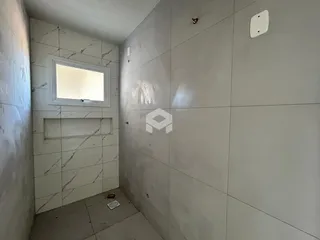 Parede interna com revestimento de azulejos claros e uma janela.