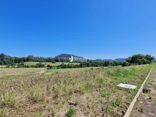 Paisagem de campos e colinas sob um céu azul.