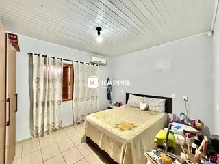 Quarto com cama e cortinas brancas em um imóvel.