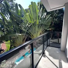 Vista da varanda com vegetação exuberante e grade de proteção.