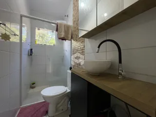 Foto interna de um banheiro com box de vidro e azulejos brancos.
