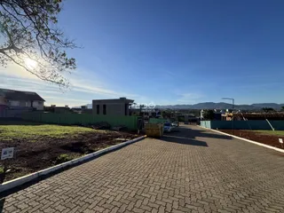 Vista externa de uma propriedade com paisagismo e área de acesso pavimentada.