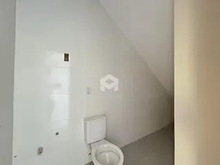 Vista de um corredor com porta e vaso sanitário em uma residência.