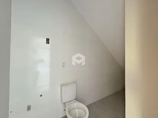 Vista de um corredor com porta e vaso sanitário em uma residência.