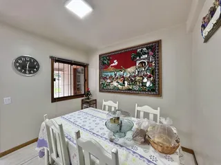 Uma sala de jantar com mesa e cadeiras brancas em um ambiente claro.