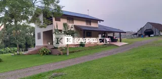Fachada de uma casa residencial com telhado de telhas e gramado ao redor.
