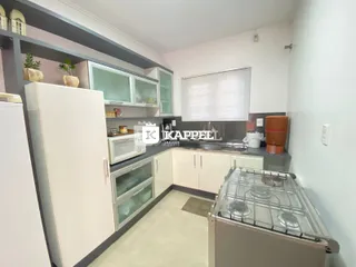 Cozinha moderna com armários brancos e fogão de aço inoxidável.