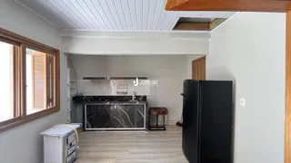 Vista da cozinha com bancada de mármore e geladeira preta.