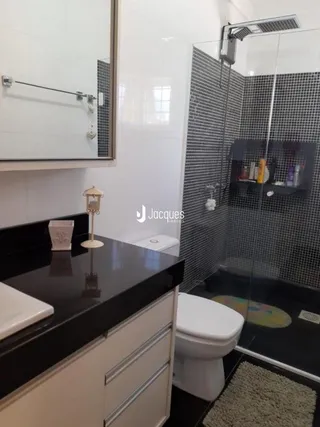 Foto de um banheiro com piso cerâmico e box de vidro.