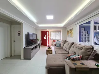 Sala de estar com sofá e televisão em ambiente claro.