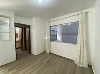 Vista interna de um ambiente com piso de madeira clara e paredes brancas.
