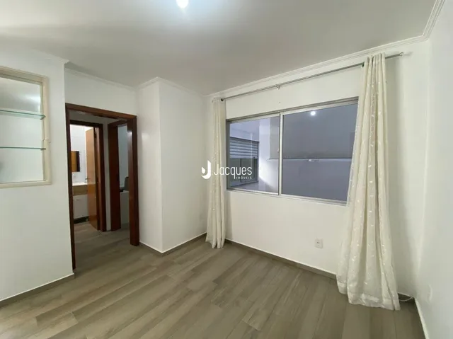 Vista interna de um ambiente com piso de madeira clara e paredes brancas.