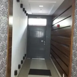 Corredor interno com paredes brancas e painéis de madeira escura.