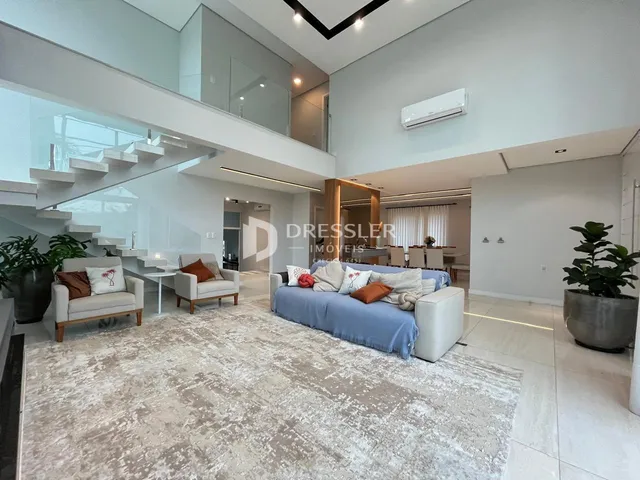 Sala de estar moderna com escadaria e área de jantar em um imóvel no Brasil.
