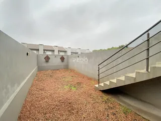 Área externa com muro de concreto e escadaria de acesso.