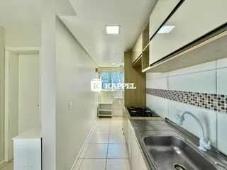 Uma foto de um corredor que leva a uma cozinha moderna com bancadas e pia.