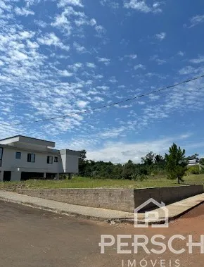 Vista externa da propriedade com muro baixo e vegetação ao fundo.